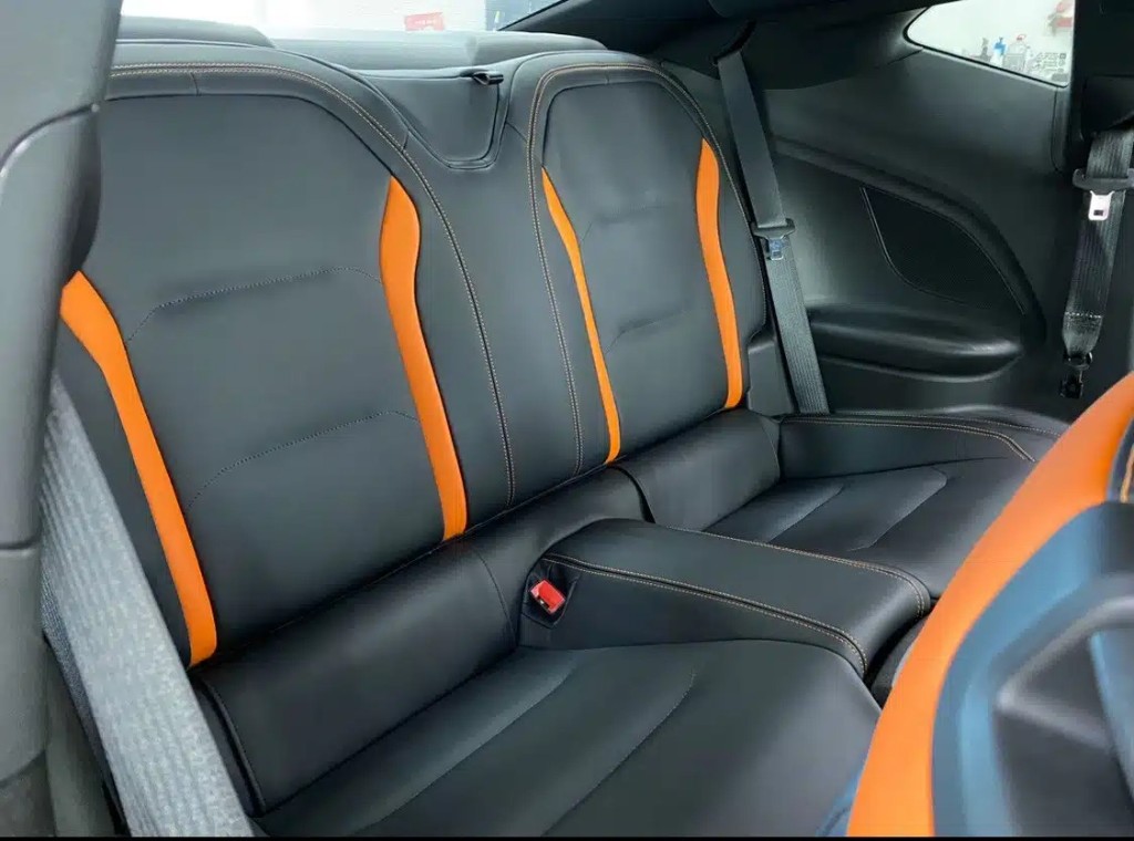 Chevrolet Camaro — задний ряд: два отдельных сиденья с оранжевыми акцентами на боковых поддержках, центральный подлокотник, контрастная оранжевая строчка