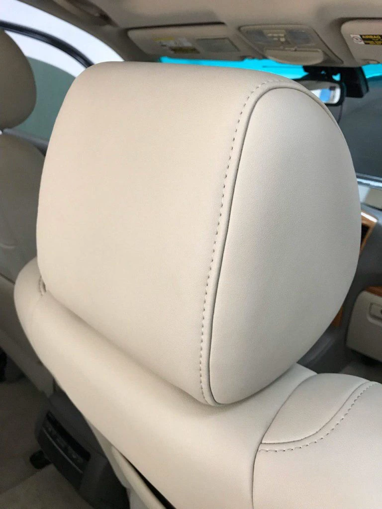 Крупный план подголовника Lexus GX470 после перетяжки бежевой экокожей с ровной строчкой